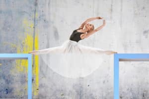 Ballerina im Spagat zwischen zwei Podesten, elegante Pose in modernem künstlerischen Umfeld – Armin Mumper.