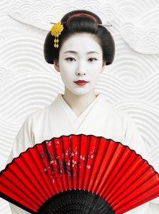 Porträt einer Geisha in Weiß mit rotem Fächer vor stilisiertem Hintergrund. Elegante Menschen-Kunst – Armin Mumper.